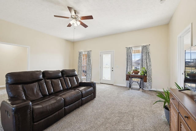 living area with a textured ceiling, baseboards, a ceiling fan, and light colored carpet