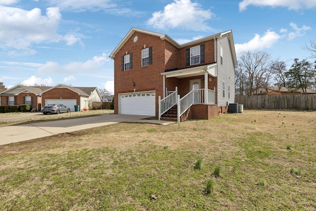 traditional-style home featuring cooling unit, a garage, brick siding, driveway, and a front yard