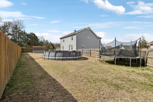 view of yard with a fenced backyard, a trampoline, and a fenced in pool