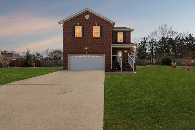 traditional-style house with driveway, fence, a lawn, and brick siding