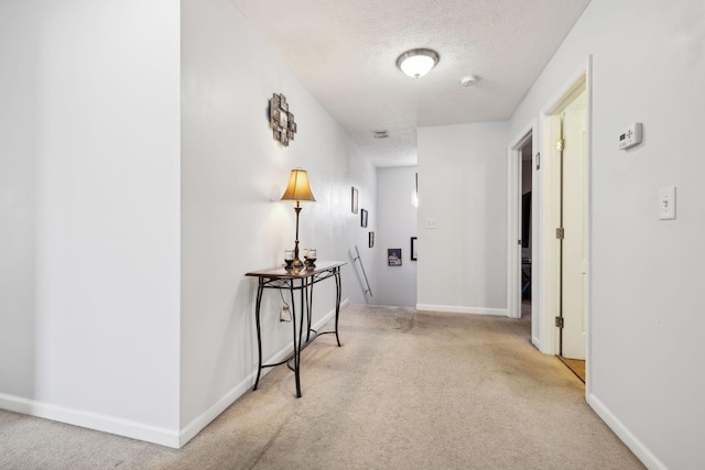 hall featuring carpet floors, a textured ceiling, and baseboards