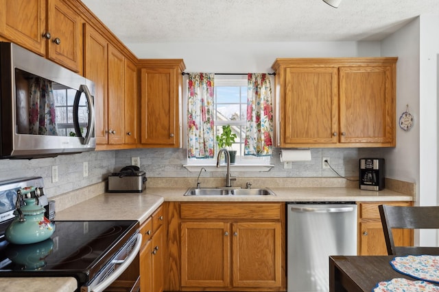 kitchen featuring stainless steel appliances, light countertops, decorative backsplash, brown cabinetry, and a sink