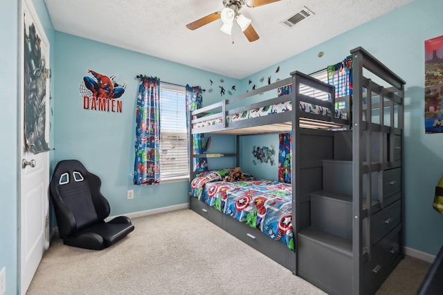 bedroom featuring baseboards, visible vents, a ceiling fan, a textured ceiling, and carpet floors