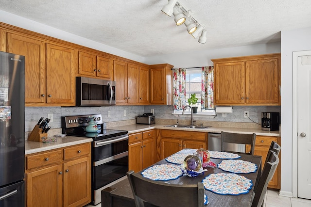 kitchen with tasteful backsplash, appliances with stainless steel finishes, light countertops, and a sink