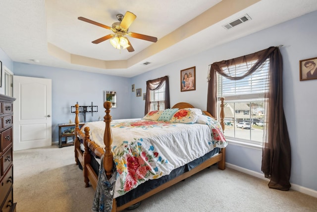 bedroom featuring a raised ceiling, visible vents, light carpet, and baseboards