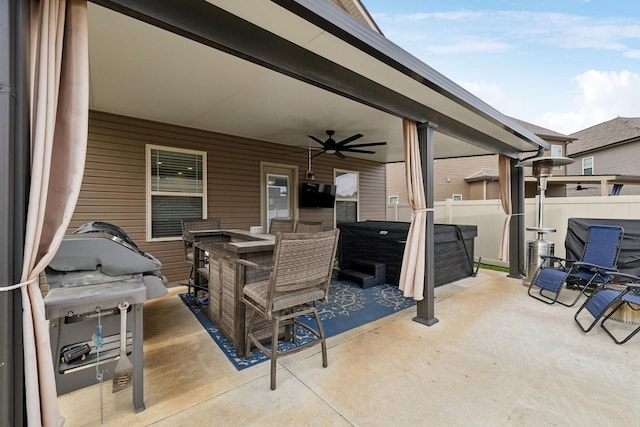 view of patio featuring outdoor dining area, fence, a hot tub, and ceiling fan