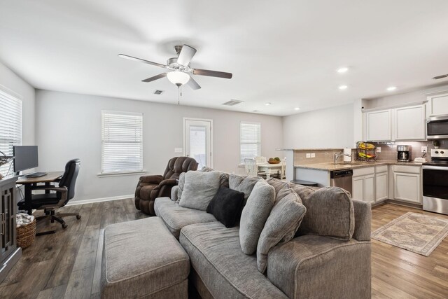 living area featuring a wealth of natural light, visible vents, and wood finished floors