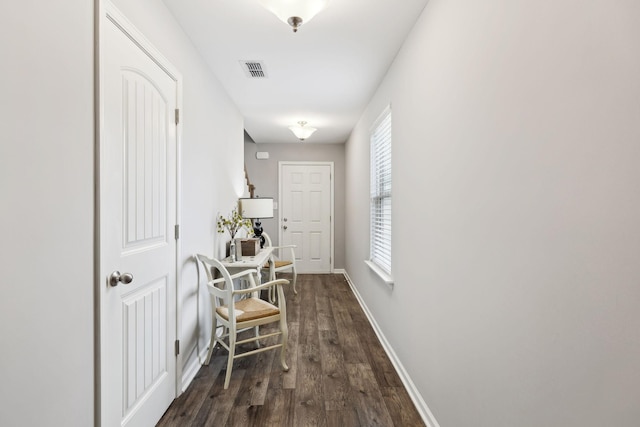 hall featuring dark wood-style floors, visible vents, and baseboards