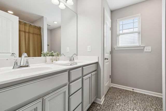 bathroom with double vanity, baseboards, and a sink