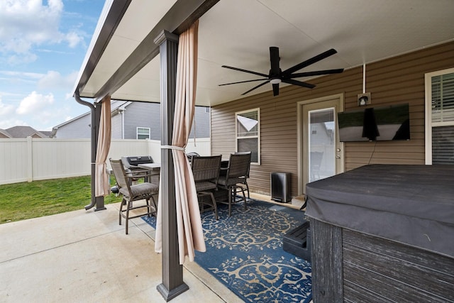 view of patio / terrace featuring a hot tub, fence, outdoor dining area, and a ceiling fan