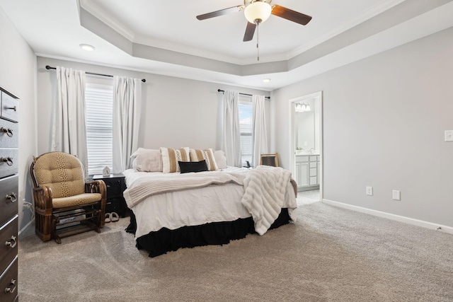 carpeted bedroom with a tray ceiling, crown molding, baseboards, and ensuite bathroom