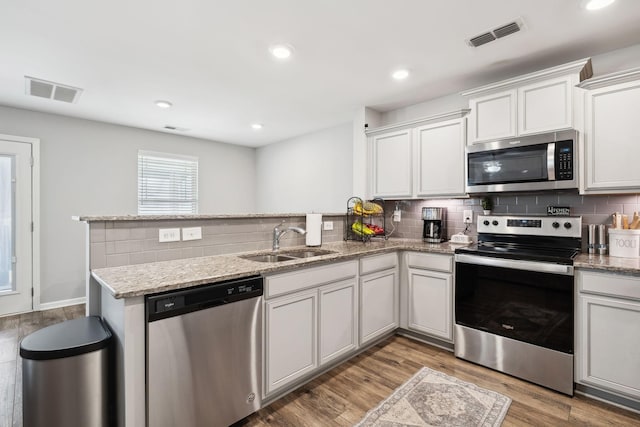 kitchen featuring stainless steel appliances, visible vents, a sink, and a peninsula