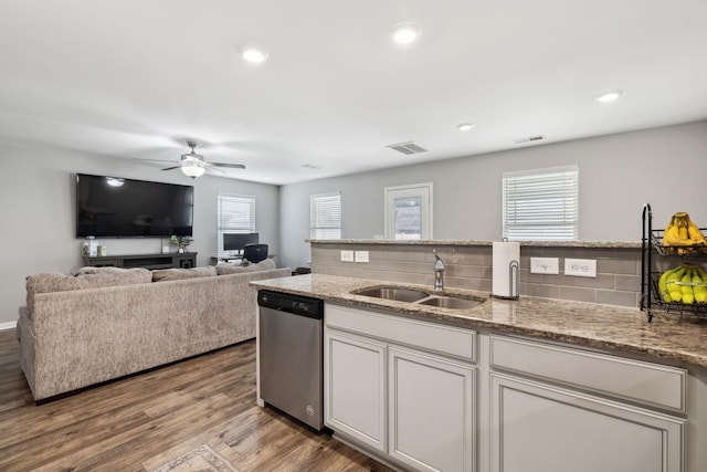 kitchen featuring visible vents, backsplash, wood finished floors, stainless steel dishwasher, and a sink