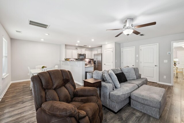 living room with dark wood-type flooring, visible vents, and baseboards