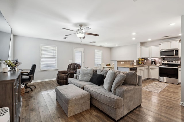 living area featuring dark wood-style floors, baseboards, visible vents, and recessed lighting