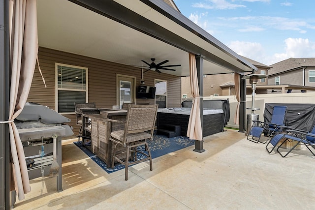 view of patio with outdoor dining area, a hot tub, grilling area, ceiling fan, and fence