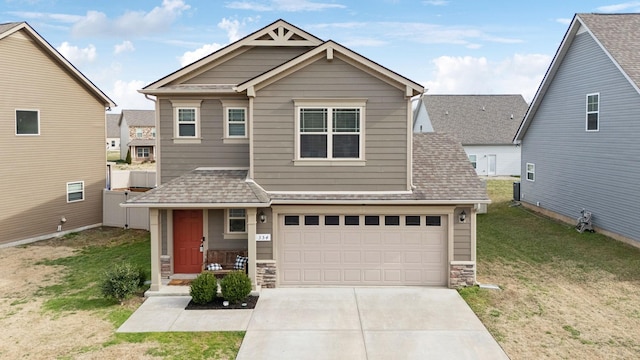 view of front of home with a front yard, stone siding, roof with shingles, and driveway