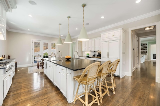 kitchen featuring dark wood-style floors, dark countertops, a kitchen island with sink, and a sink