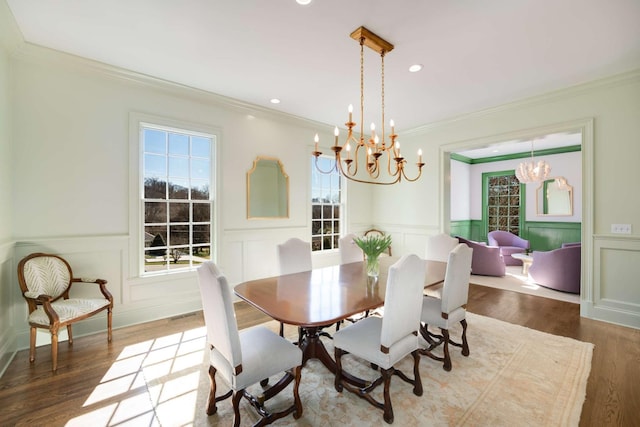 dining space featuring a healthy amount of sunlight, crown molding, a chandelier, and wood finished floors