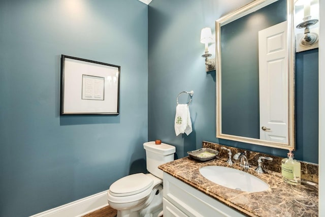 bathroom featuring baseboards, vanity, and toilet