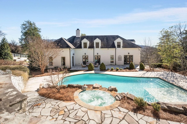 back of house with stucco siding, french doors, a patio area, and an in ground hot tub