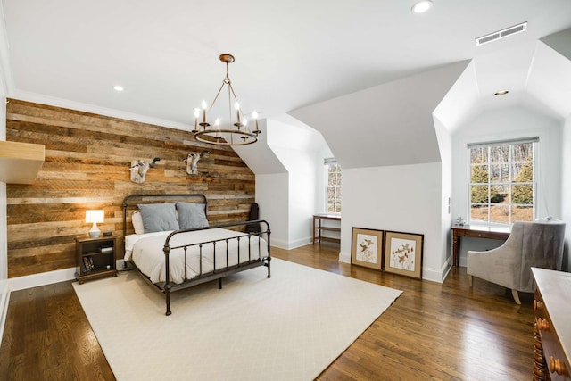 bedroom with lofted ceiling, wood walls, wood finished floors, and visible vents