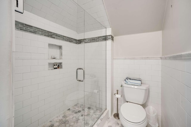 full bath with tile walls, wainscoting, a shower stall, and toilet