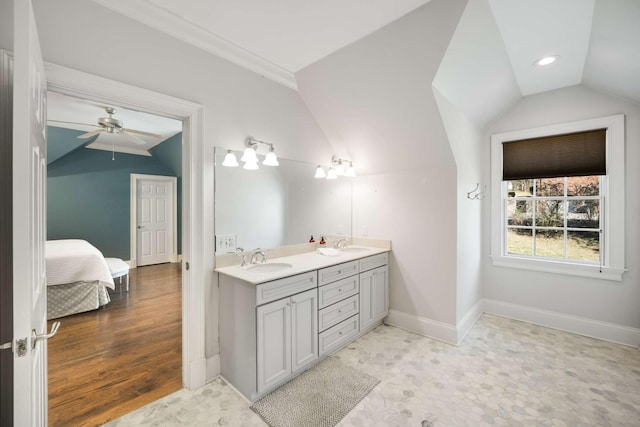 ensuite bathroom featuring double vanity, baseboards, vaulted ceiling, and a sink