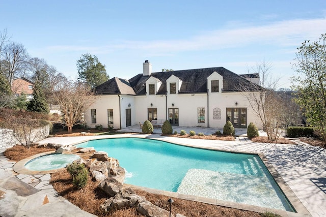 rear view of house featuring an outdoor pool, a patio, an in ground hot tub, french doors, and stucco siding