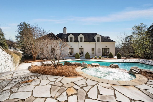 rear view of property with a patio area, an outdoor pool, a chimney, and stucco siding