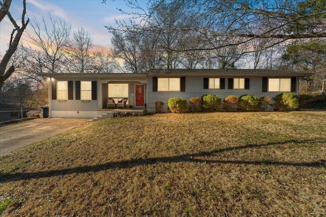 single story home with driveway and a lawn