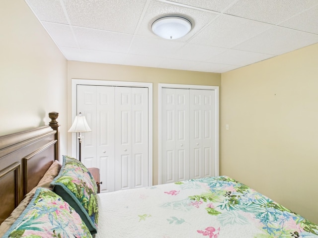 bedroom featuring a drop ceiling and two closets