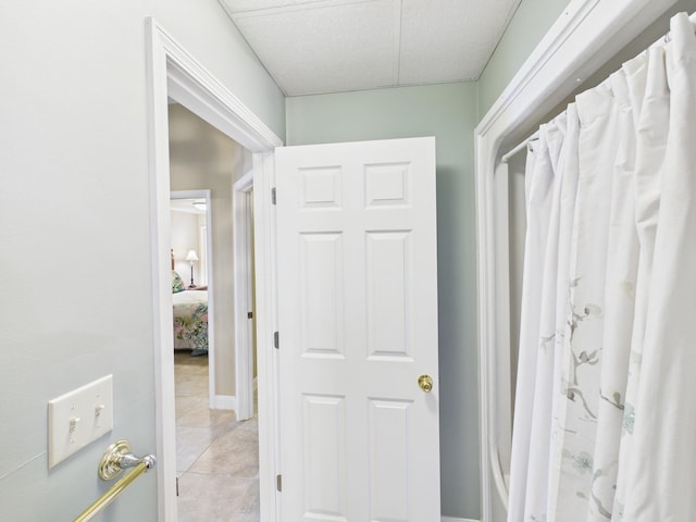 hallway featuring light tile patterned flooring and a paneled ceiling