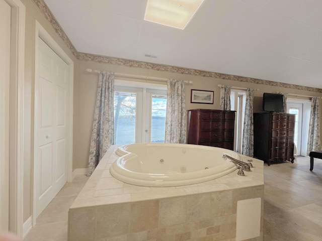 full bathroom featuring tile patterned flooring, a tub with jets, and baseboards