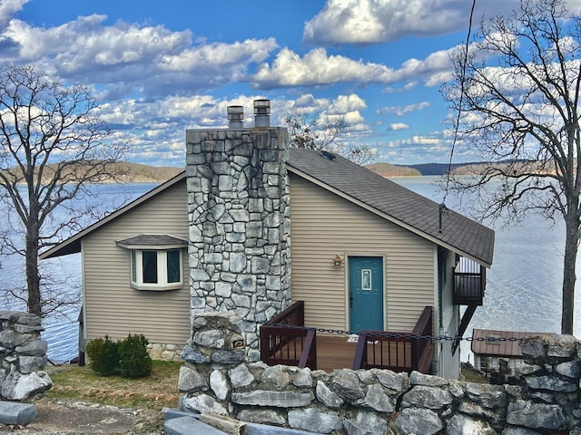 view of property exterior featuring a shingled roof and a chimney