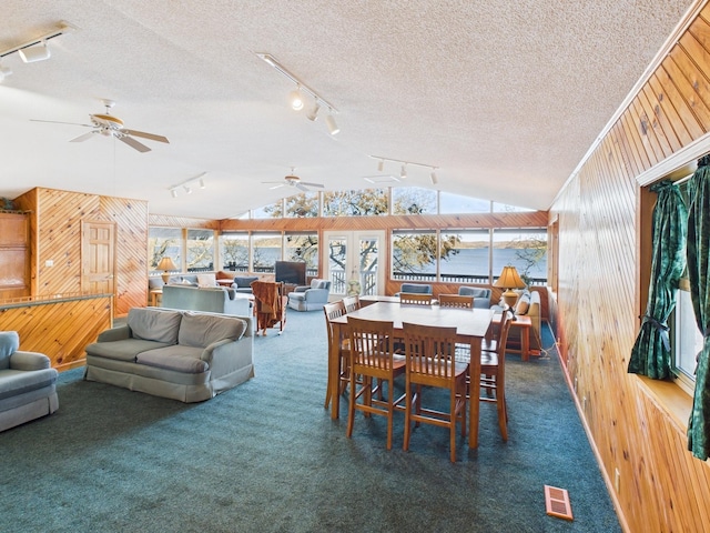 dining area with vaulted ceiling, carpet floors, a textured ceiling, and wooden walls