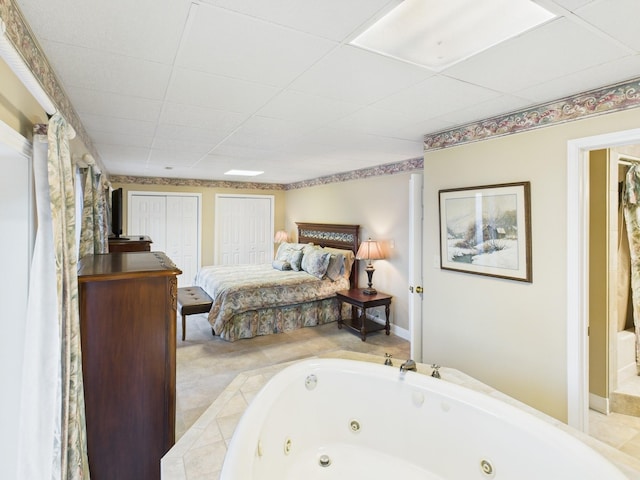 bedroom with a paneled ceiling and multiple closets