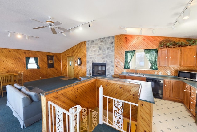 kitchen featuring wooden walls, dishwasher, stainless steel microwave, open floor plan, and vaulted ceiling