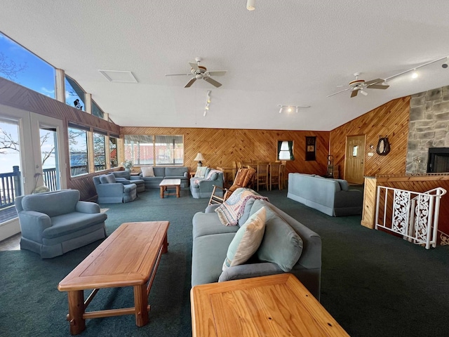 living area featuring lofted ceiling, carpet floors, wood walls, and a textured ceiling