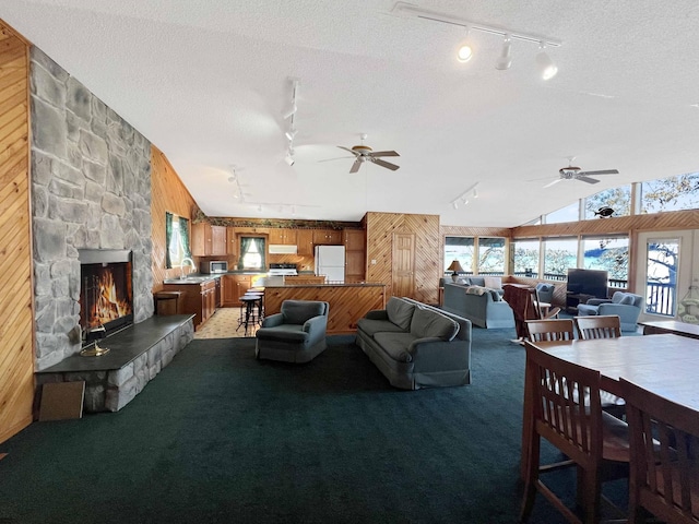 living area featuring a stone fireplace, light carpet, vaulted ceiling, and wooden walls