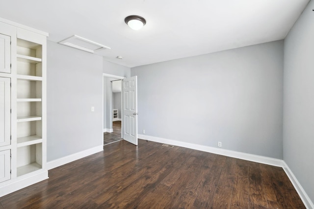 unfurnished bedroom featuring visible vents, wood finished floors, attic access, and baseboards