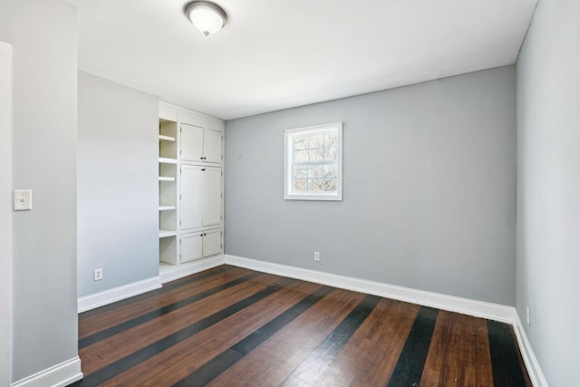 unfurnished bedroom featuring baseboards and dark wood finished floors