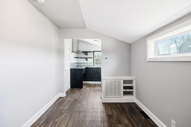 interior space featuring dark wood-style floors, visible vents, vaulted ceiling, and baseboards