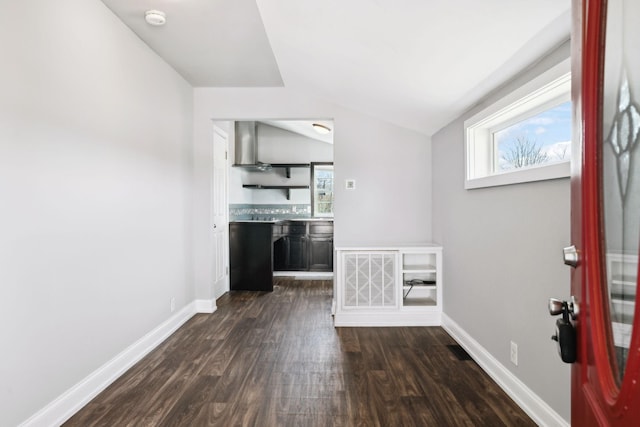 interior space with dark wood-style floors, vaulted ceiling, visible vents, and baseboards