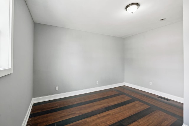 spare room featuring baseboards, visible vents, and dark wood-type flooring