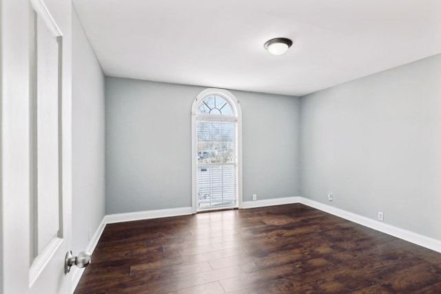 empty room with dark wood-type flooring and baseboards