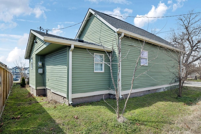 view of home's exterior with roof with shingles and a lawn