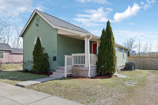 view of front facade featuring a porch, a front yard, cooling unit, and fence