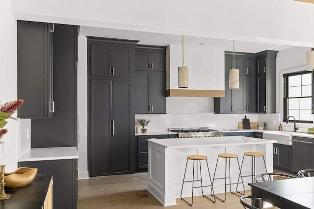 kitchen featuring dishwashing machine, light countertops, a sink, and light wood-style flooring