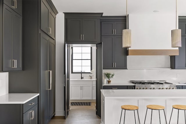 kitchen featuring light wood-type flooring, light countertops, a sink, and a kitchen bar